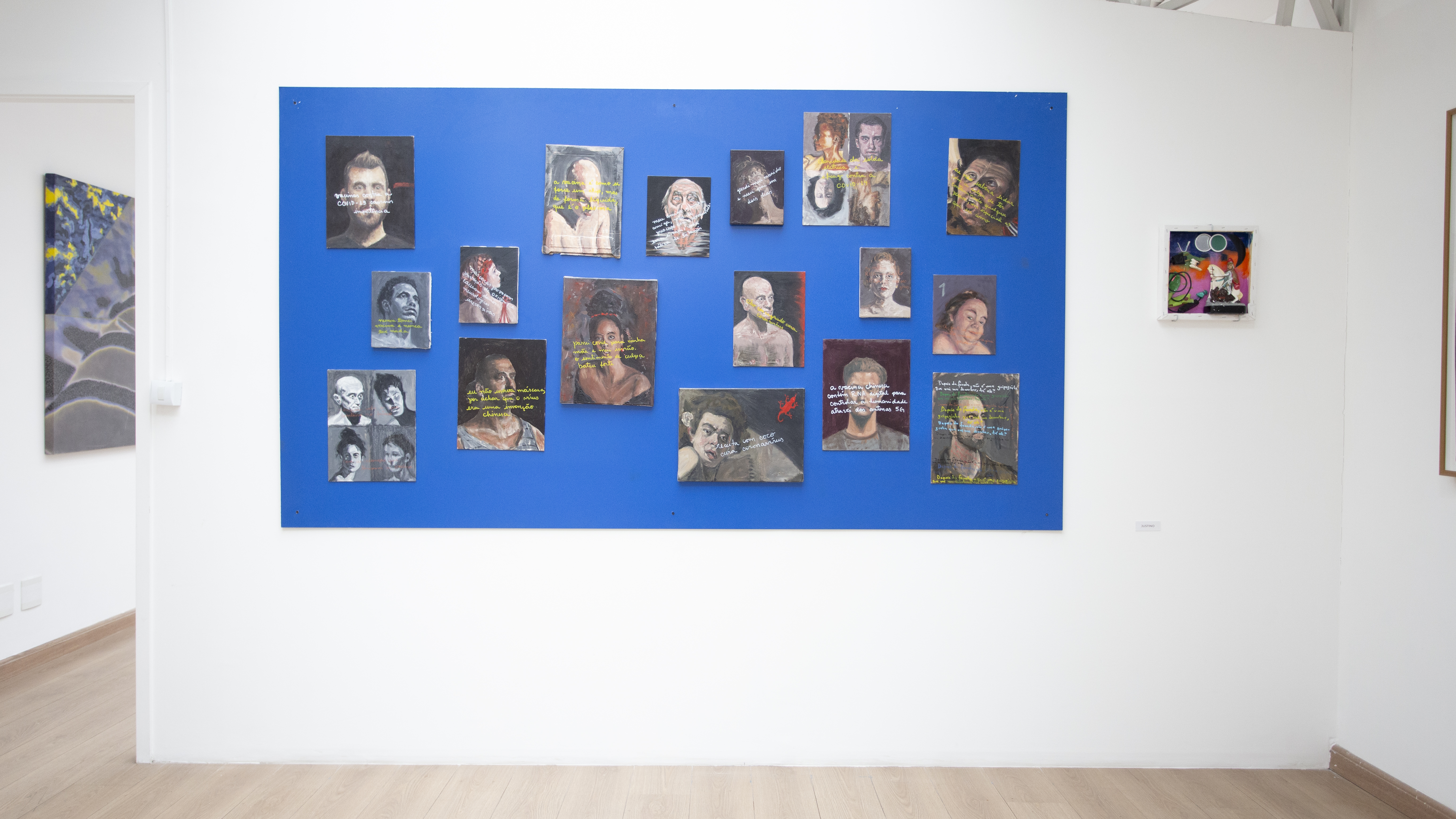Regras do Contágio, Justino, 2022. Retratos a óleo sobre diversos suportes motnados em mdf azul de 1,2 m x 2,2 m..